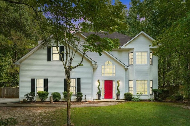 traditional-style house featuring a front yard and fence