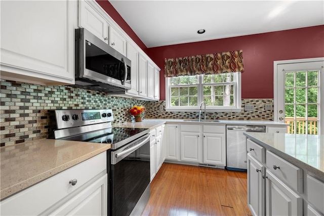 5312 Tormeal Trce, Suwanee, GA 30024 - kitchen featuring appliances with stainless steel finishes, a sink, white cabinets, decorative backsplash, and light wood-style floors
