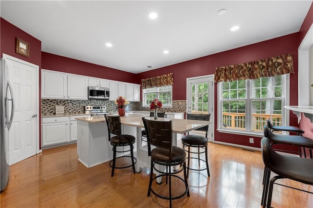 5312 Tormeal Trce, Suwanee, GA 30024 - kitchen featuring appliances with stainless steel finishes, a kitchen bar, white cabinetry, light countertops, and recessed lighting