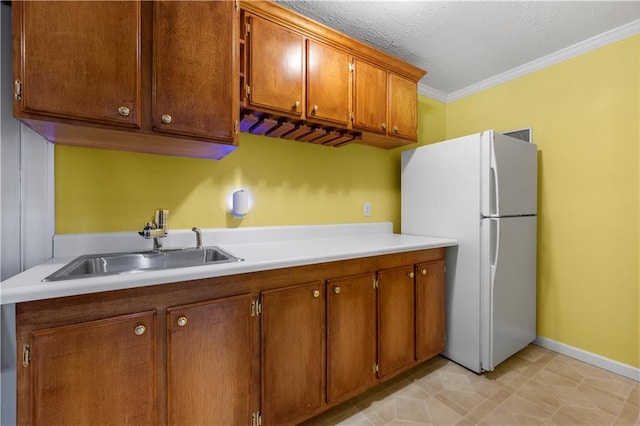 5312 Tormeal Trce, Suwanee, GA 30024 - kitchen with freestanding refrigerator, a sink, ornamental molding, brown cabinets, and light countertops
