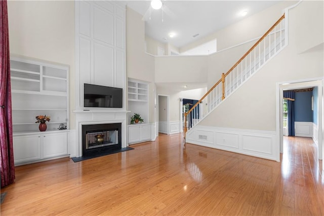 5312 Tormeal Trce, Suwanee, GA 30024 - unfurnished living room with light wood-style flooring, stairs, a high ceiling, built in features, and a large fireplace