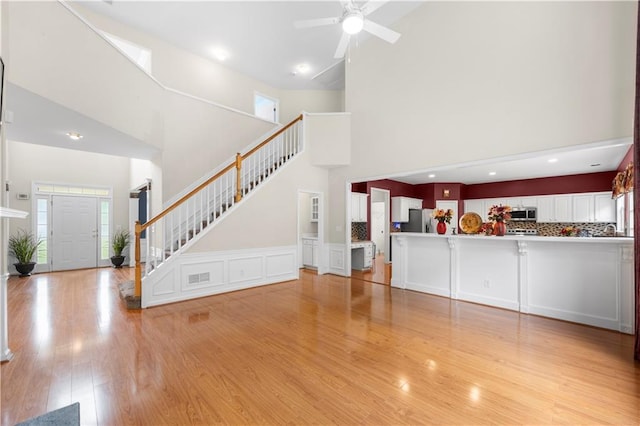 5312 Tormeal Trce, Suwanee, GA 30024 - unfurnished living room featuring a towering ceiling, stairway, plenty of natural light, light wood-style floors, and ceiling fan