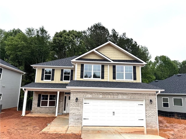 view of front of property featuring a garage, brick siding, driveway, view of wooded area, and a porch