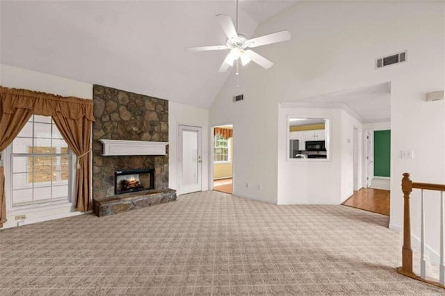 unfurnished living room featuring ceiling fan, high vaulted ceiling, a stone fireplace, and carpet flooring