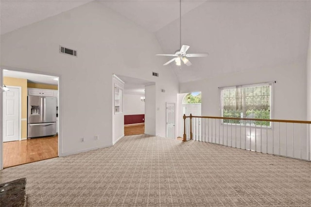 carpeted spare room with ceiling fan and high vaulted ceiling