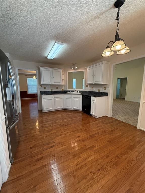 kitchen with stainless steel fridge, black dishwasher, decorative light fixtures, white cabinets, and sink