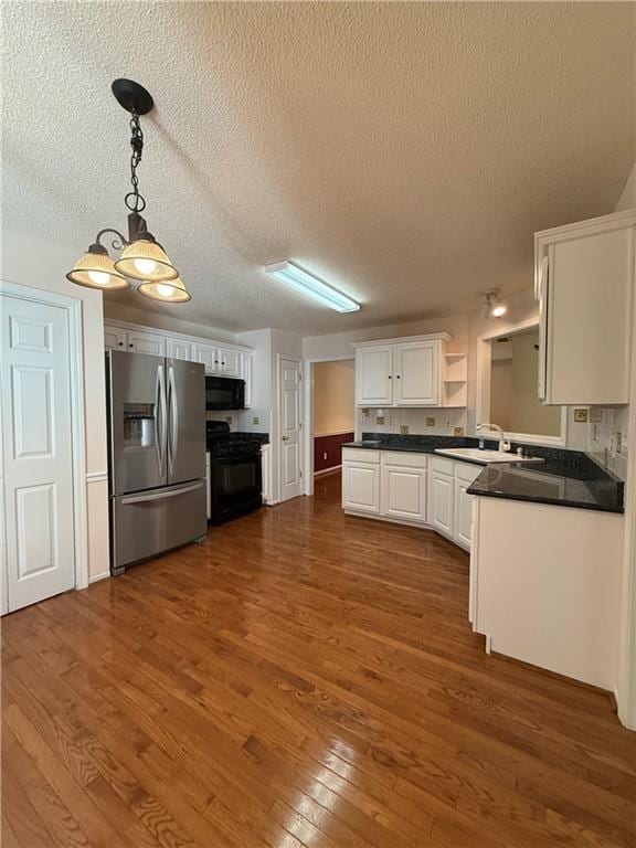 kitchen featuring a textured ceiling, black appliances, decorative light fixtures, white cabinetry, and sink