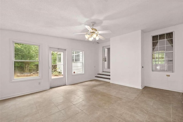 tiled spare room with a textured ceiling and ceiling fan