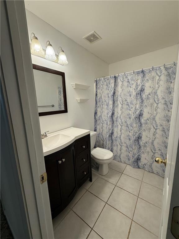 bathroom with toilet, vanity, tile patterned flooring, and a shower with shower curtain