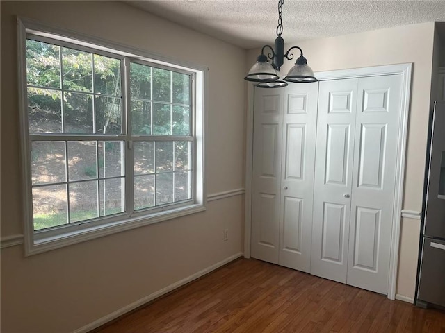 unfurnished dining area featuring hardwood / wood-style floors, a chandelier, and a textured ceiling