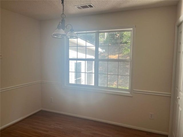 spare room featuring dark hardwood / wood-style floors, a chandelier, and a textured ceiling