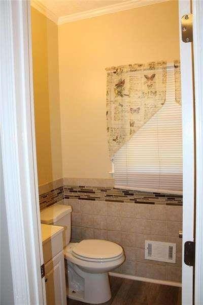 2031 Lakewood Cir, Grayson, GA 30017 - bathroom featuring ornamental molding, toilet, tile walls, wainscoting, and vanity