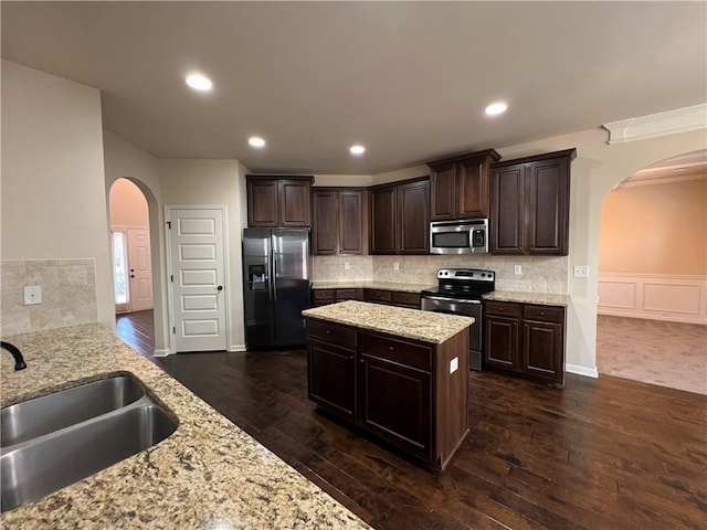 kitchen featuring sink, light stone counters, dark brown cabinets, and appliances with stainless steel finishes