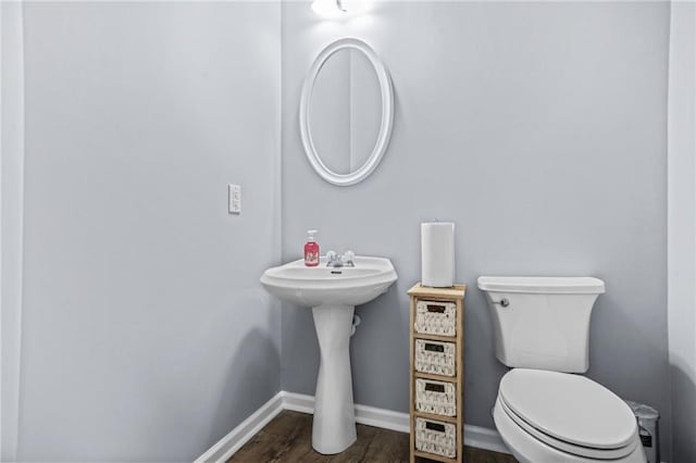 bathroom with baseboards, toilet, and wood finished floors