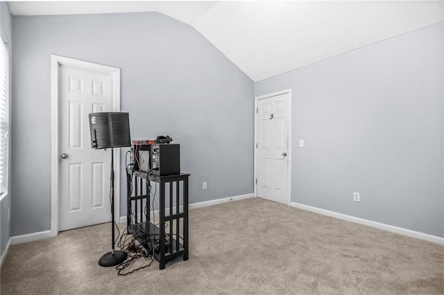 interior space featuring lofted ceiling, carpet flooring, and baseboards