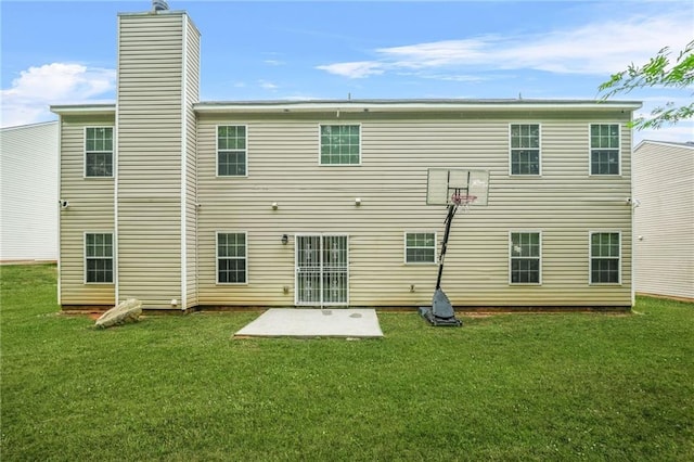 rear view of house featuring a yard, a chimney, and a patio
