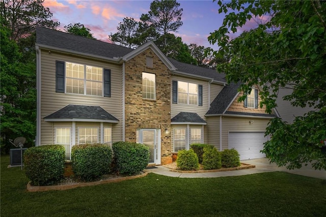 colonial house with concrete driveway, a front yard, and brick siding