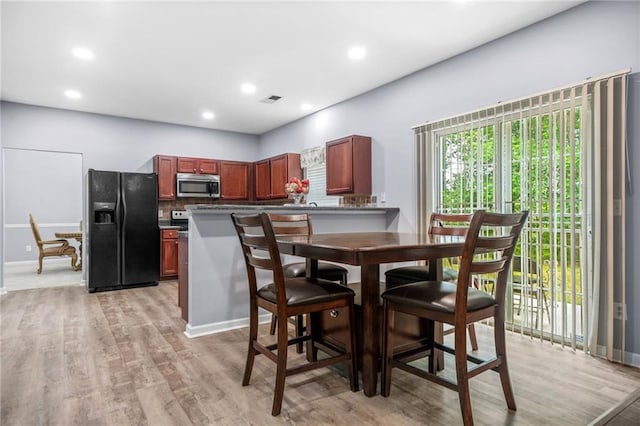 kitchen featuring baseboards, visible vents, stainless steel microwave, black fridge, and light wood-type flooring
