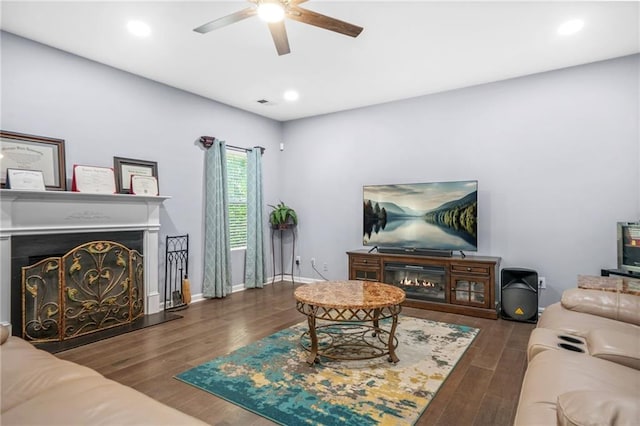 living area featuring a lit fireplace, ceiling fan, recessed lighting, and wood finished floors