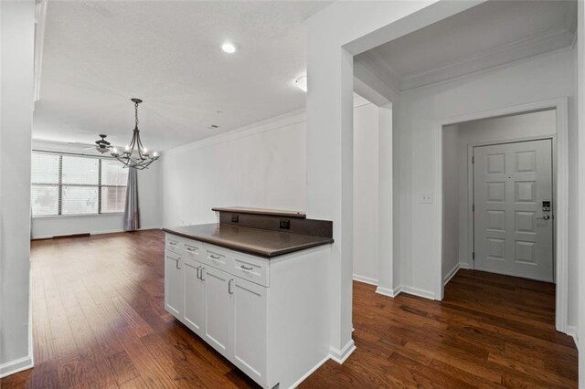400 17th St NW Unit 1321, Atlanta, GA 30363 - kitchen featuring crown molding, dark countertops, a chandelier, white cabinetry, and dark wood-type flooring