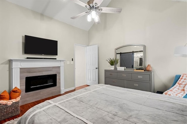 bedroom featuring wood-type flooring, high vaulted ceiling, ceiling fan, and a tiled fireplace