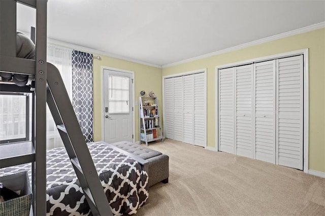 bedroom with carpet floors, crown molding, and two closets