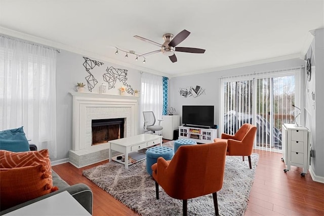 living room featuring a fireplace, wood-type flooring, ceiling fan, and crown molding