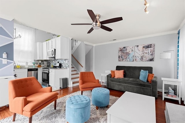 living room featuring ceiling fan with notable chandelier, dark hardwood / wood-style floors, crown molding, and track lighting