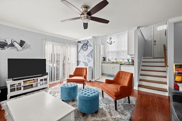 living area featuring a wealth of natural light, dark wood-type flooring, and ceiling fan with notable chandelier