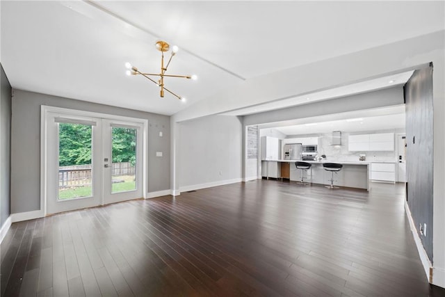 2123 Drew Valley Rd NE, Brookhaven, GA 30319 - unfurnished living room with a chandelier, baseboards, dark wood finished floors, lofted ceiling, and french doors