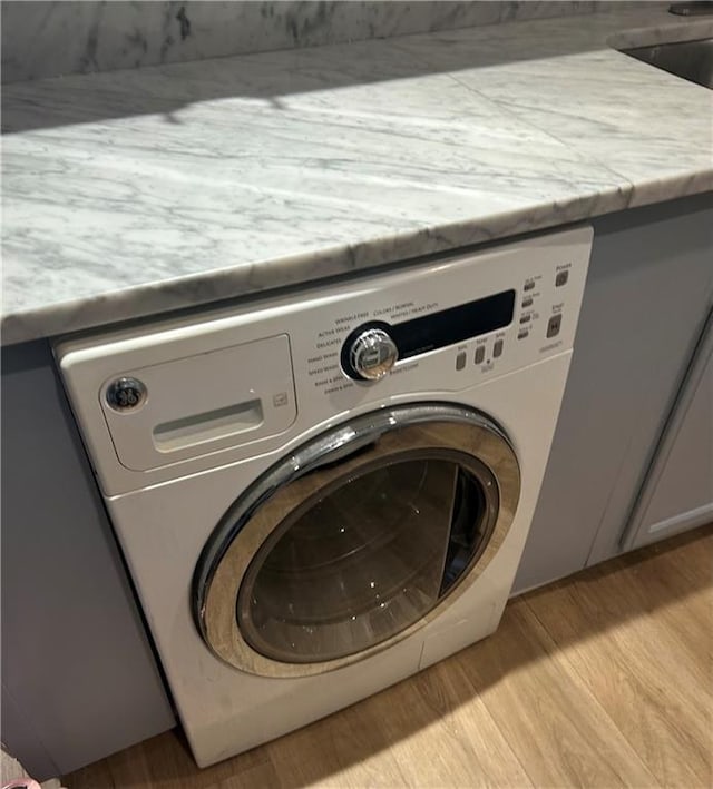 clothes washing area featuring laundry area, washer / dryer, and light wood-style floors