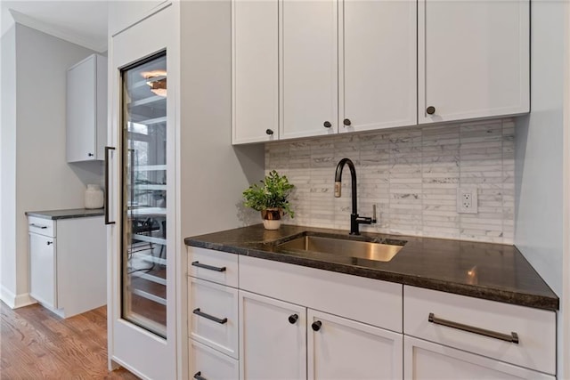 kitchen with crown molding, sink, white cabinets, light wood-type flooring, and decorative backsplash