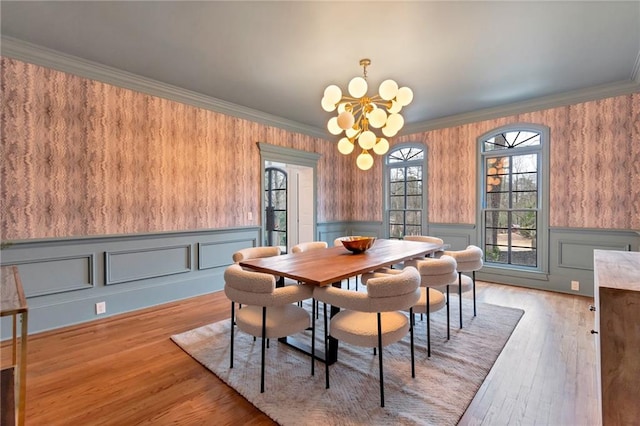 dining area with a notable chandelier, light hardwood / wood-style flooring, and crown molding