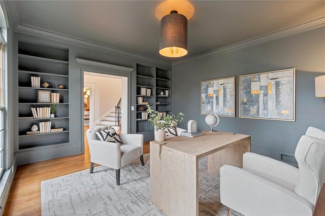 office area with built in shelves, crown molding, and hardwood / wood-style floors