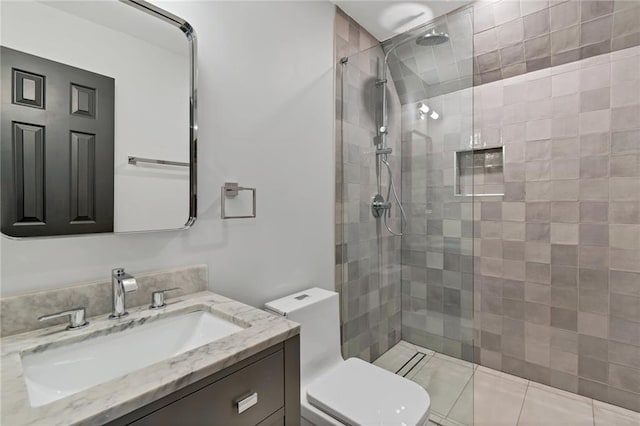 bathroom featuring vanity, toilet, tiled shower, and tile patterned flooring