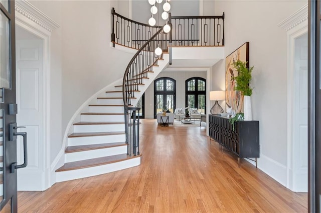 foyer entrance featuring light hardwood / wood-style flooring, a high ceiling, and french doors