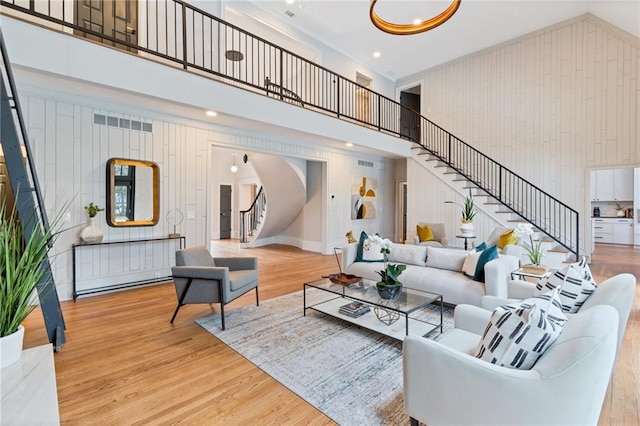 living room with hardwood / wood-style floors, a towering ceiling, and wooden walls