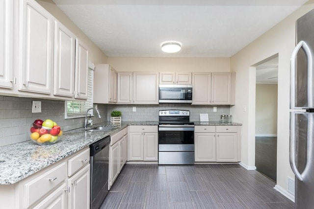 kitchen featuring light stone countertops, white cabinets, sink, and stainless steel appliances