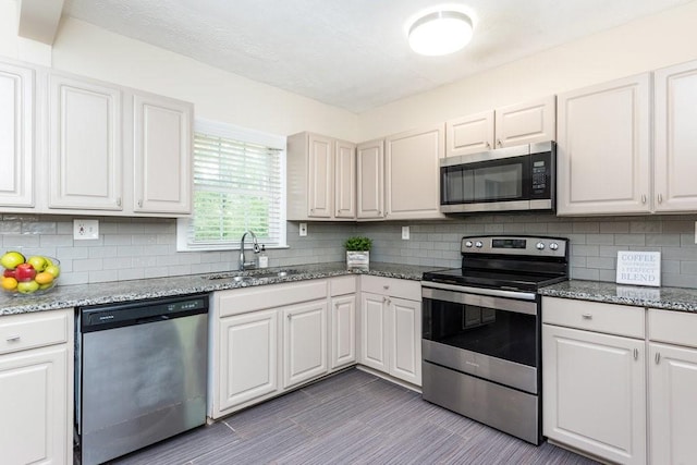 kitchen featuring stainless steel appliances, white cabinets, decorative backsplash, sink, and light stone countertops