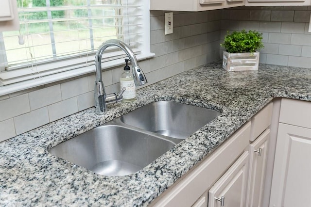 interior details featuring white cabinets, decorative backsplash, and sink