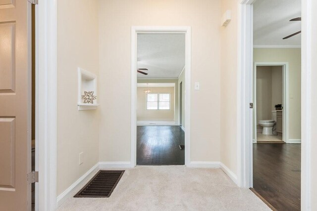 hallway with light wood-type flooring and ornamental molding