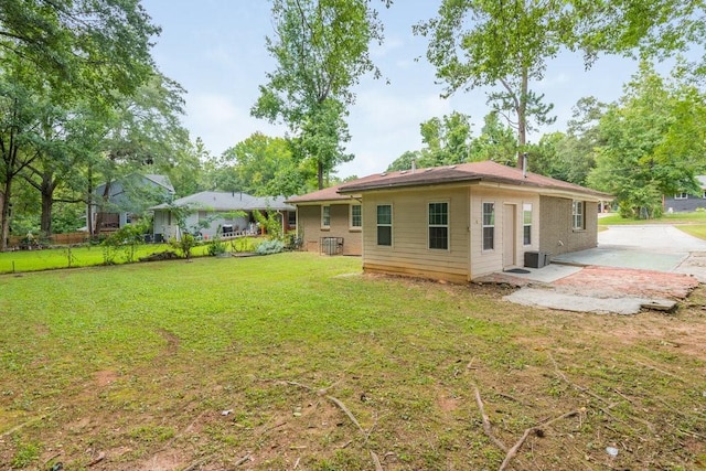 rear view of house featuring central air condition unit, a patio area, and a yard