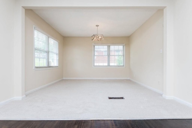 spare room featuring hardwood / wood-style flooring, plenty of natural light, and an inviting chandelier