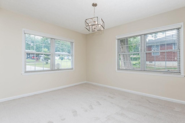 spare room featuring a chandelier, carpet flooring, and plenty of natural light