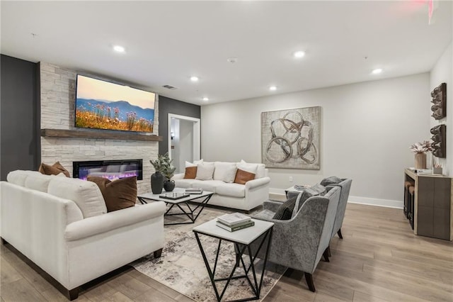 living room featuring light hardwood / wood-style floors and a stone fireplace