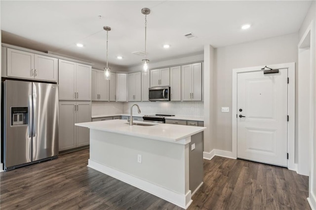 kitchen featuring gray cabinetry, a center island with sink, sink, hanging light fixtures, and stainless steel appliances