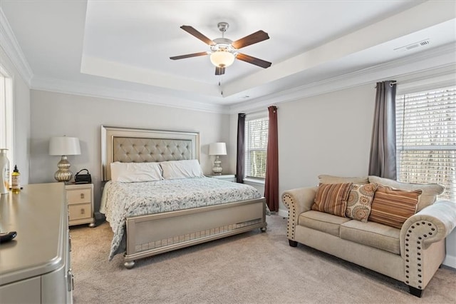 bedroom featuring light carpet, a tray ceiling, crown molding, and ceiling fan