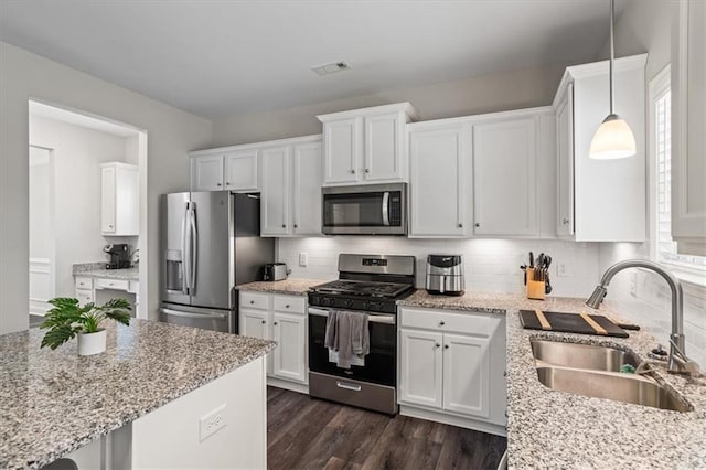 kitchen with stainless steel appliances, sink, hanging light fixtures, and white cabinets