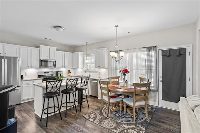 kitchen with a kitchen island, dark hardwood / wood-style floors, decorative light fixtures, white cabinets, and stainless steel appliances