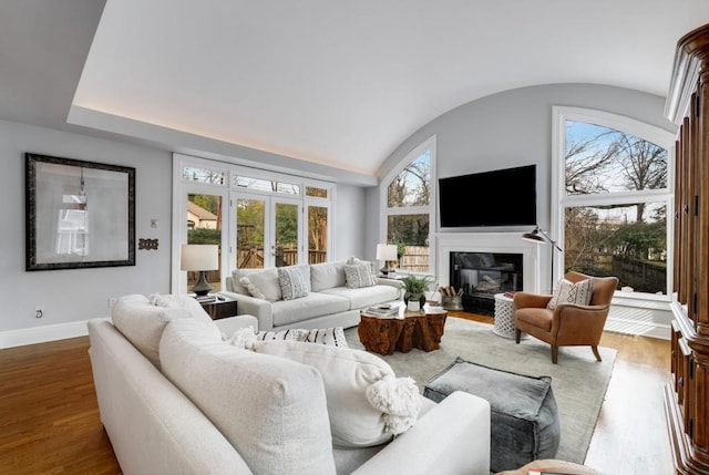 living area with a wealth of natural light, lofted ceiling, baseboards, and wood finished floors